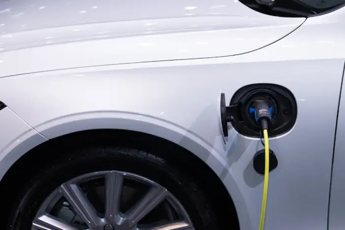 Free A white electric car is plugged in for charging, close-up view of the charging port. Stock Photo