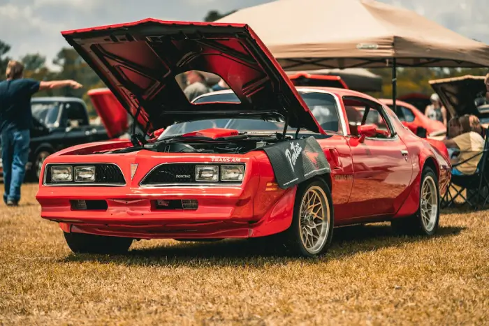 Free Vintage red Pontiac Trans Am with hood open on display at an outdoor car show. Stock Photo