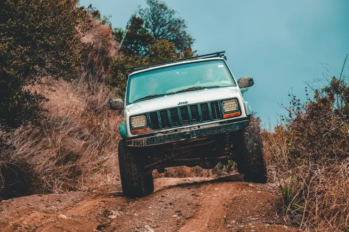 Free A rugged Jeep navigating a challenging muddy offroad trail through dense forest. Stock Photo