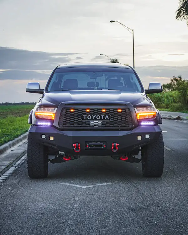 Free Front view of a Toyota pickup truck parked on an open road during dusk, showcasing its robust design. Stock Photo