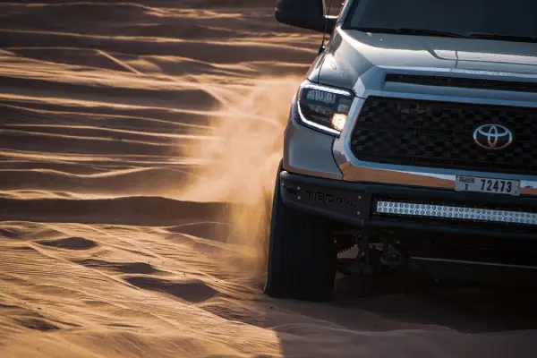 Free Close-up shot of a Toyota truck navigating desert sand, stirring up dust. Stock Photo