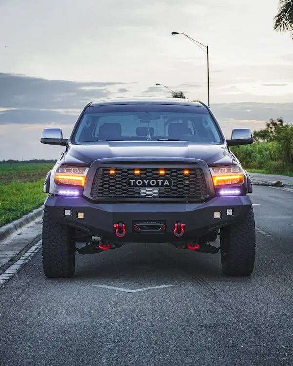 Free Front view of a Toyota pickup truck parked on an open road during dusk, showcasing its robust design. Stock Photo